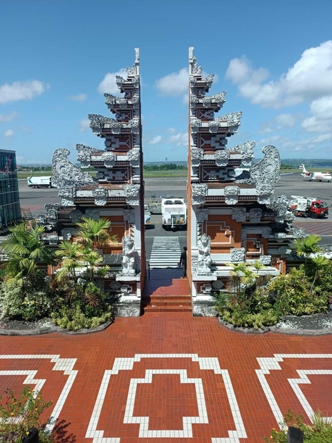 Balinese gate at an airport with aircraft in the background.