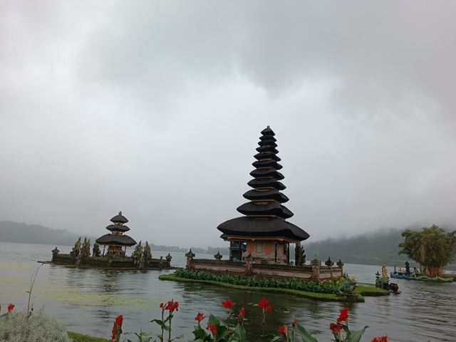 Iconic Balinese temple on a lake surrounded by mist and greenery.