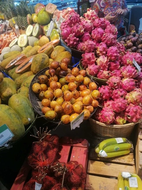 Market display of assorted fruits including dragon fruits and passion fruits.