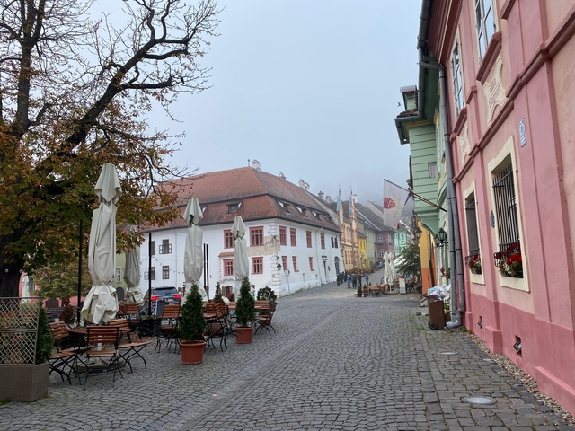 Cobbled street with colorful buildings and outdoor seating.