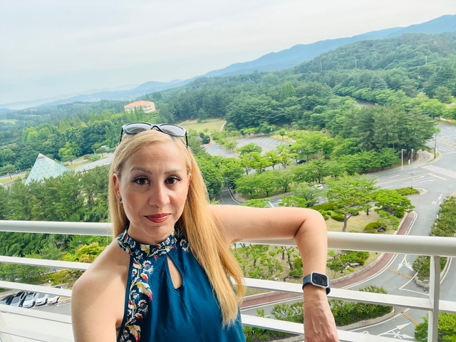 Person posing with a view of a verdant landscape behind.