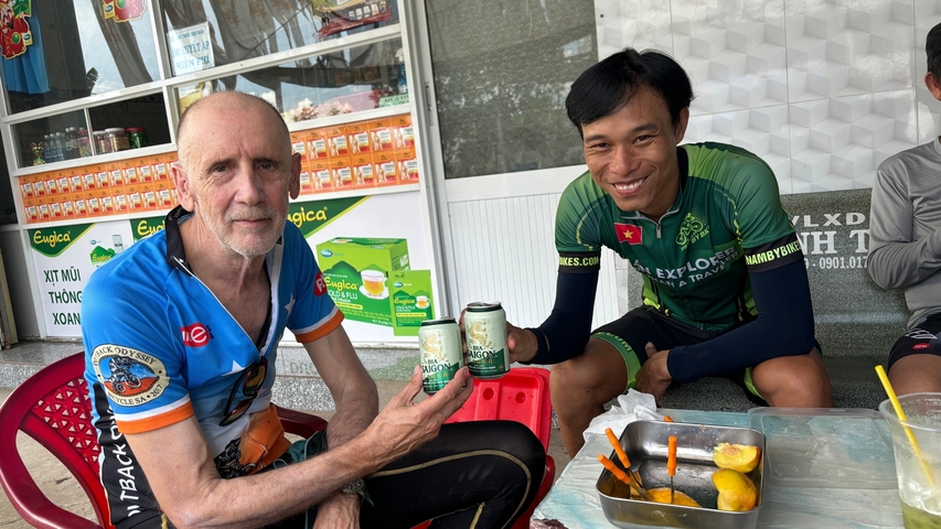       Two people sitting outside with drinks and a meal.
  