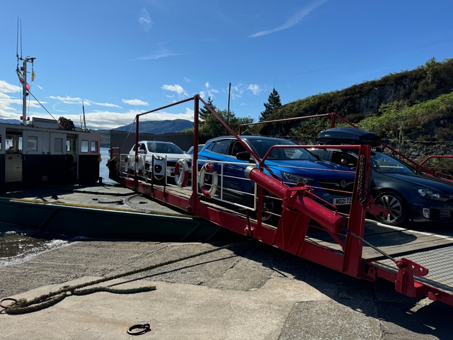 Car ferrying multiple vehicles across a lake.