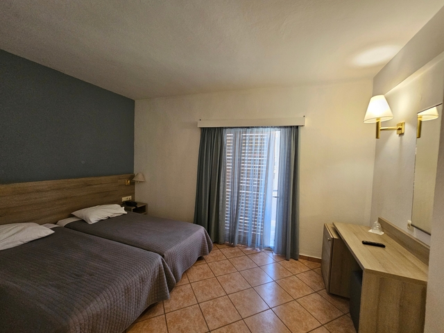       Simple hotel room with twin beds and a balcony door.
  