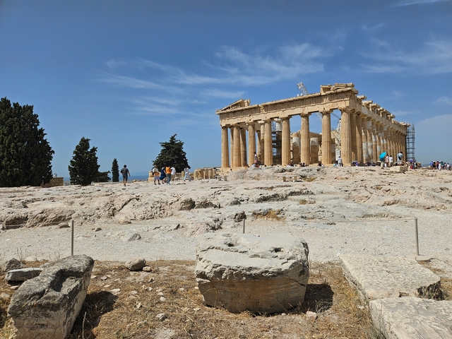      The Parthenon temple ruin in Athens with tourists visiting.
  