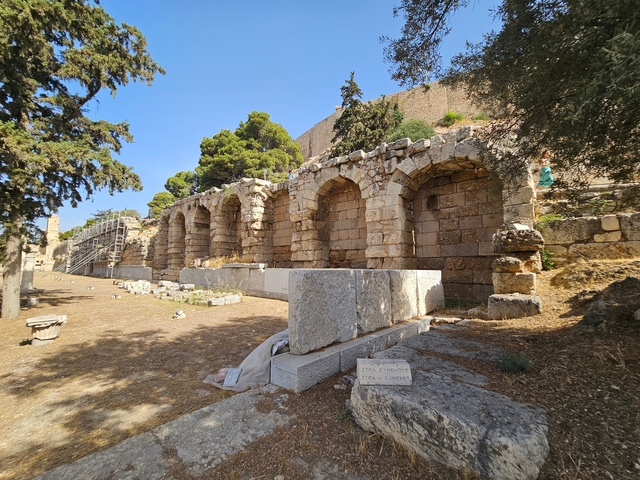       Ancient stone structure with arches and a grassy area.
  
