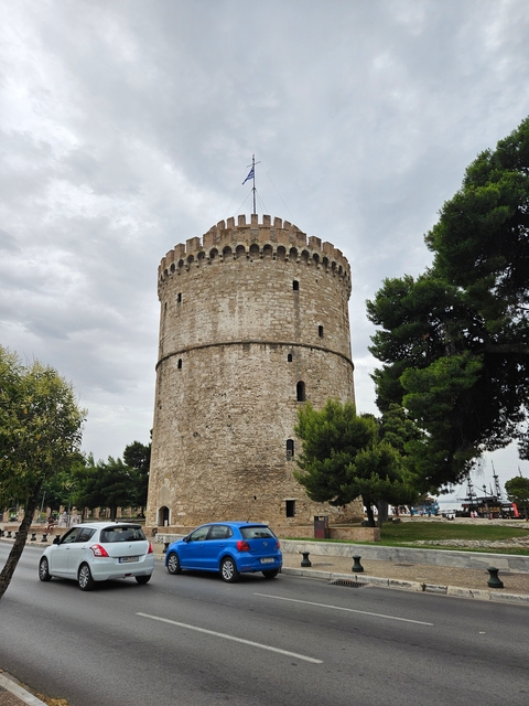       A circular tower with surrounding trees under a cloudy sky.
  