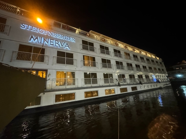       Night view of a cruise ship docked at a river.
  