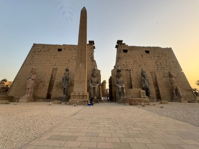       The Luxor Temple at sunset with statues and an obelisk.
  