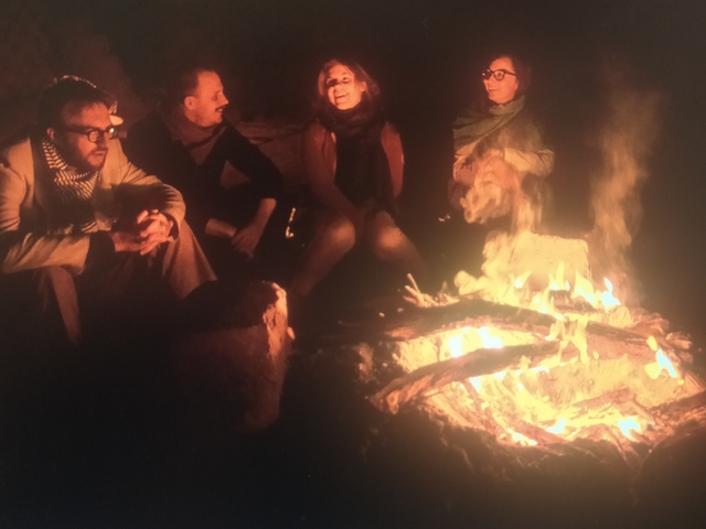 People sitting around a campfire at night.