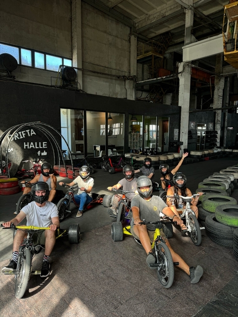 Group of people on motorized tricycles indoors, wearing helmets.