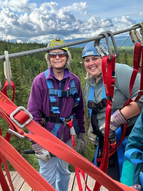 Two women in harnesses for an outdoor adventure activity.