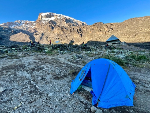       Tent set up at a base camp with mountain views in the background.
  