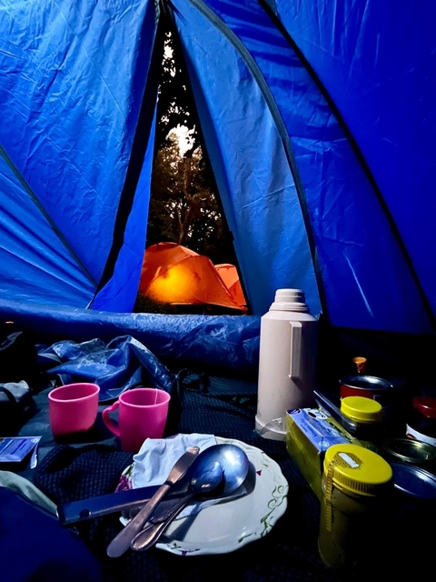 Inside a tent with views of other tents illuminated at night.