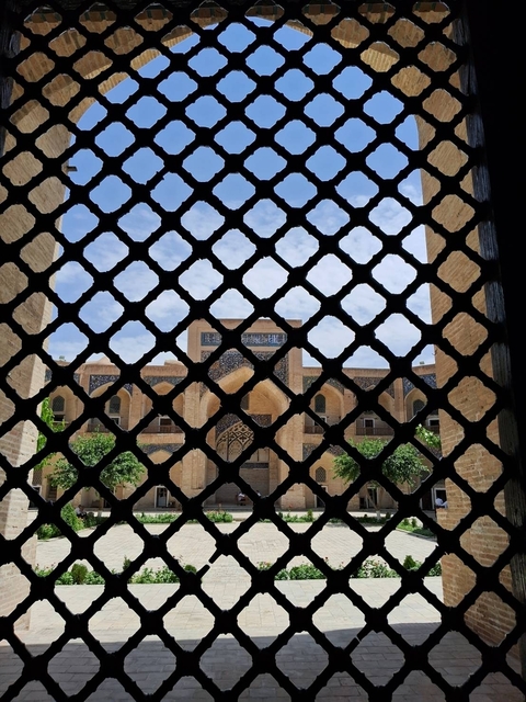       Architectural detail seen through a decorative lattice frame.
  