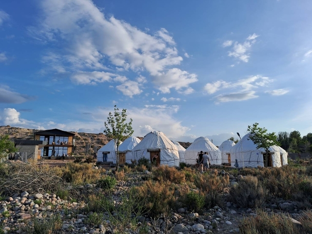       Yurt camp in a scenic rural setting under a blue sky.
  
