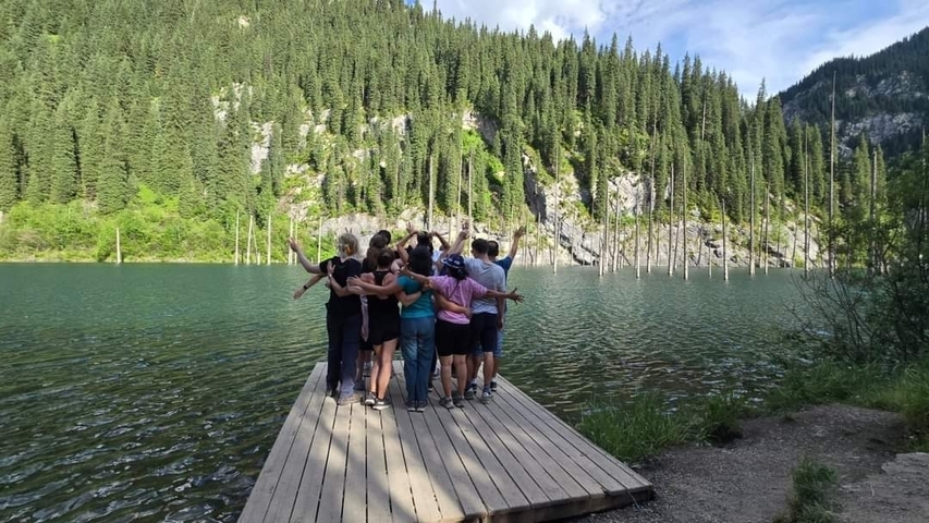       Group of people standing on a dock overlooking a tranquil lake.
  