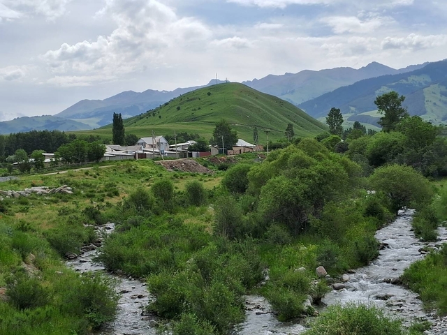       Pastoral countryside with green hills and a small river.
  