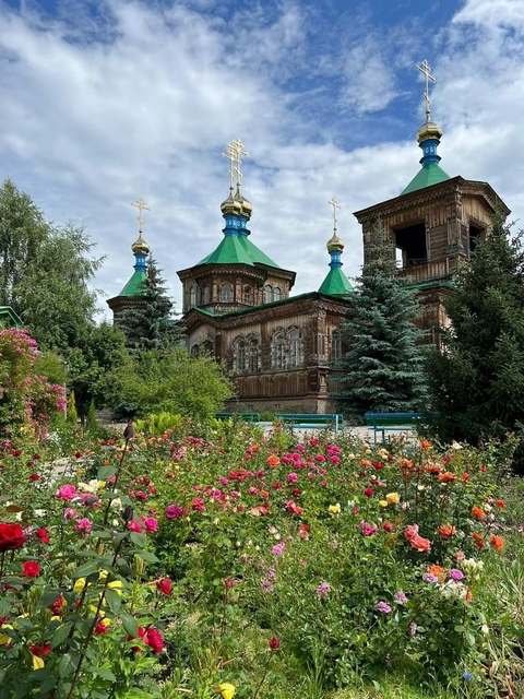       Beautiful church with colorful domes and lush garden.
  