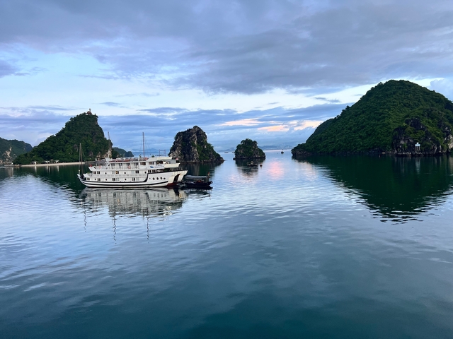 A large boat on calm waters with karst formations.