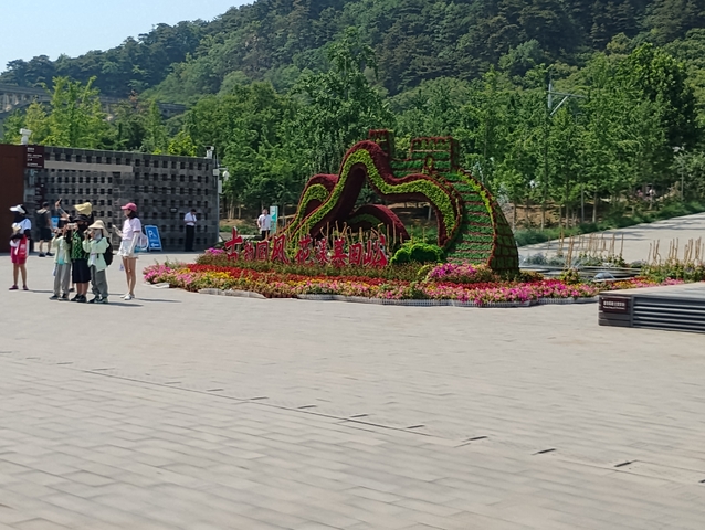       Park environment with a large floral arrangement and people.
  
