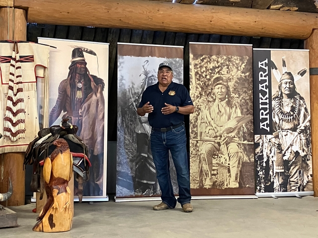 Man speaking in front of native American displays and banners.