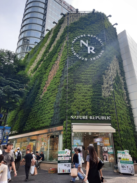       Building facade covered in greenery with Nature Republic signage.
  