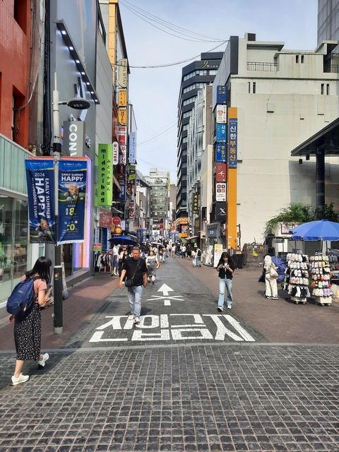       Bustling city street with shops and pedestrians.
  