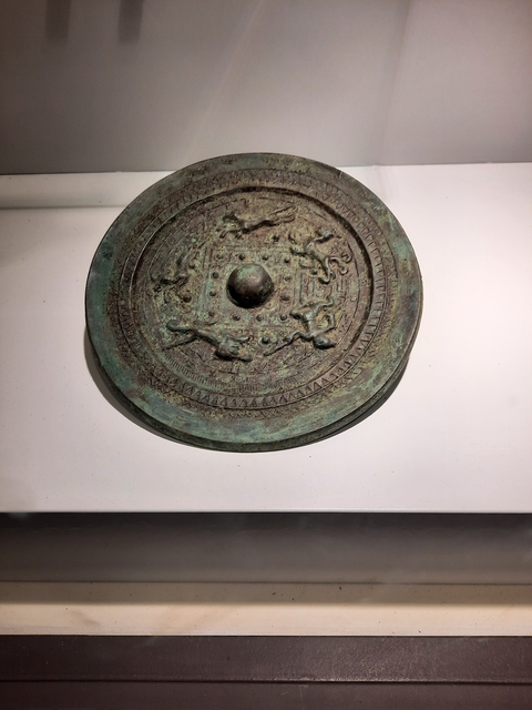       Close-up of a detailed bronze circular artifact.
  