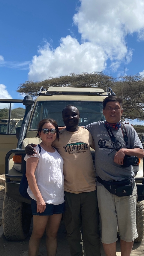 Group of people posing in front of a safari vehicle.