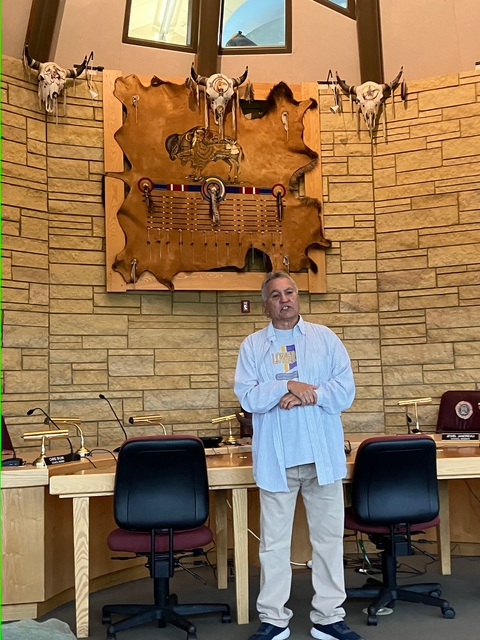 A speaker standing in an indoor setting with cultural decor.