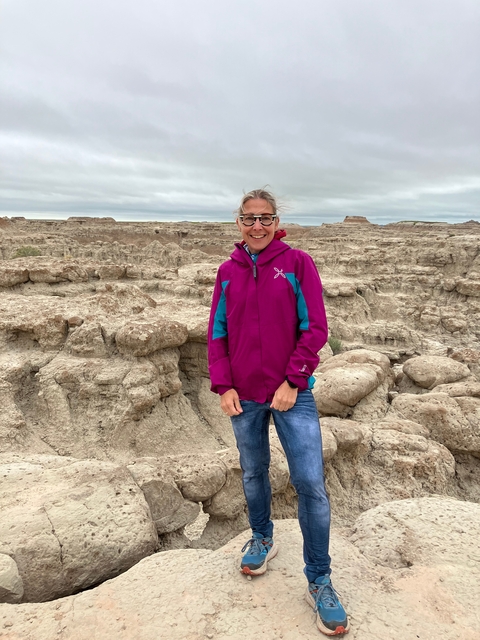 A person in a colorful jacket standing in a rocky landscape.