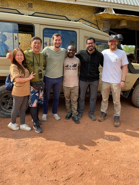       A group of people standing close to a safari vehicle.
  