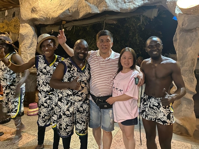 A group of people posing together at night, some in traditional attire.