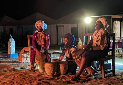       People performing music around a campfire at night.
  