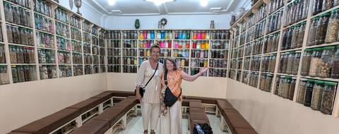 People inside a shop with large shelves of colorful spices.