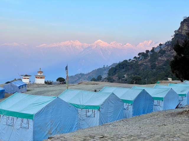 Tents set up with a view of mountains at sunrise.