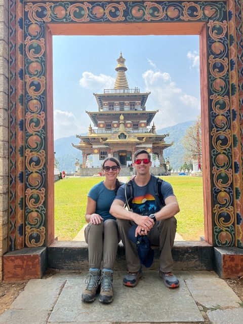 Couple sitting in front of a decorated temple.