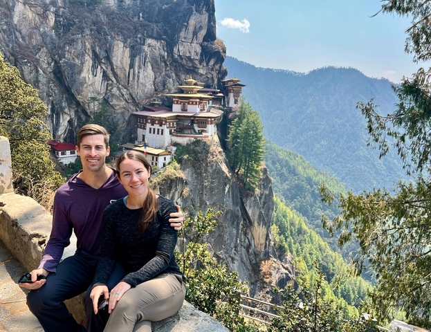 Couple with a view of a monastery on a cliff.