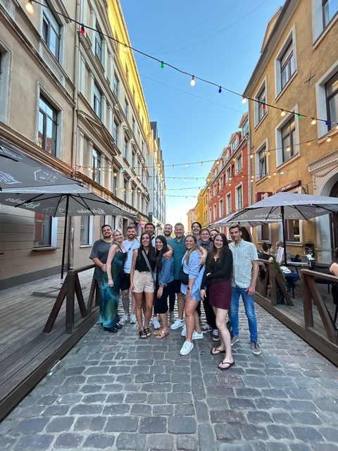 Group posing in a narrow street with string lights.