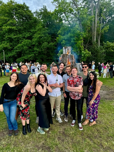 Festive group gathering outdoors with large bonfire.