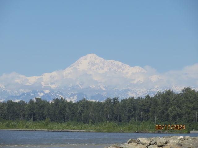       Snow-capped mountain with cloudy sky, forest in foreground.
  