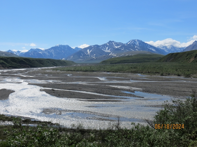      River cutting through mountainous landscape with clear skies.
  