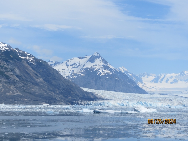       Mountain and glacier landscape with icy water in foreground.
  