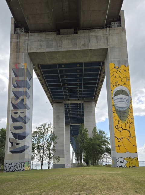 Columns of a bridge with colorful murals, viewed from below.