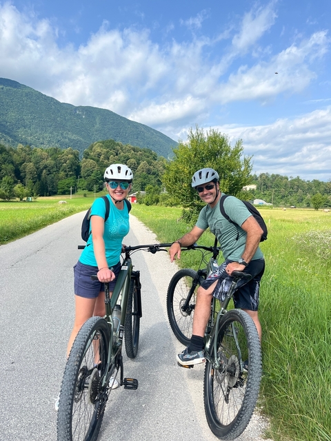       Two people with bicycles on a country road.
  