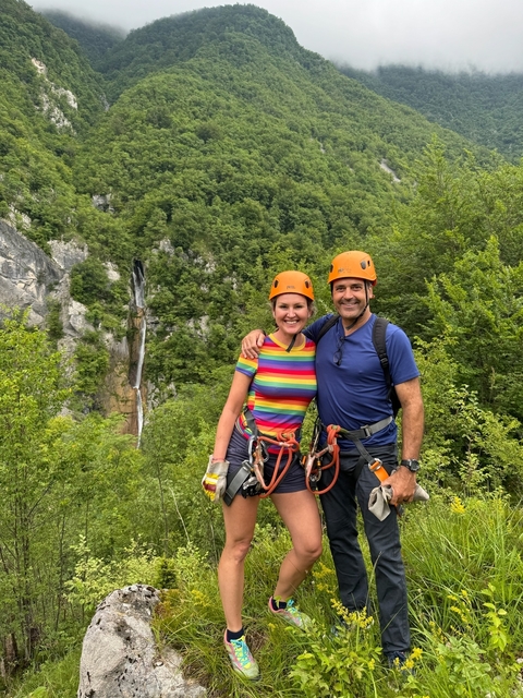      Two people in climbing gear with a waterfall in the background.
  