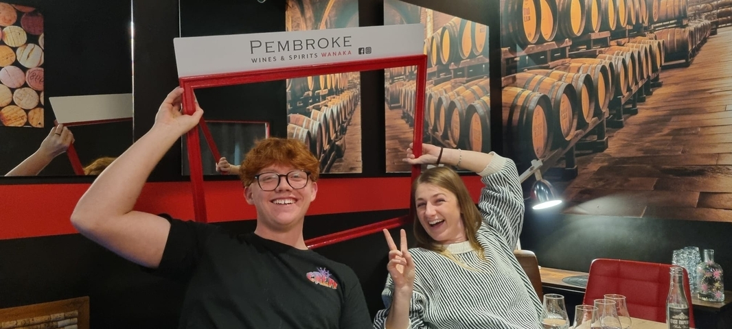       Two people with a Pembroke frame in a wine-themed room.
  
