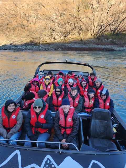 A group of people in a boat wearing life jackets.