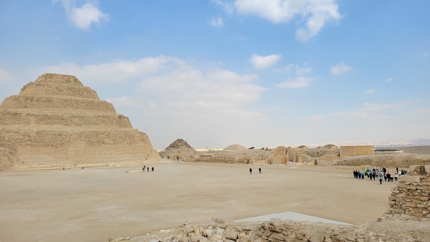 Wide view of a stepped pyramid in a desert area.
